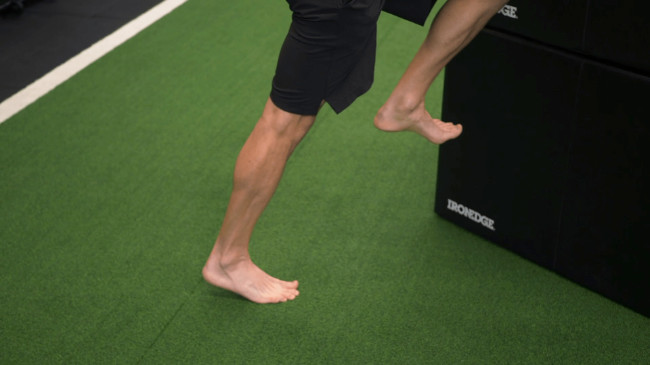 A coach demonstrating standing calf isometric holds