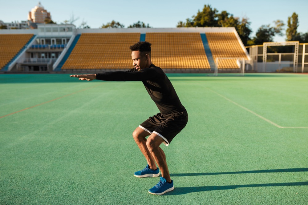 A young athlete outdoors practicing bodyweight squats