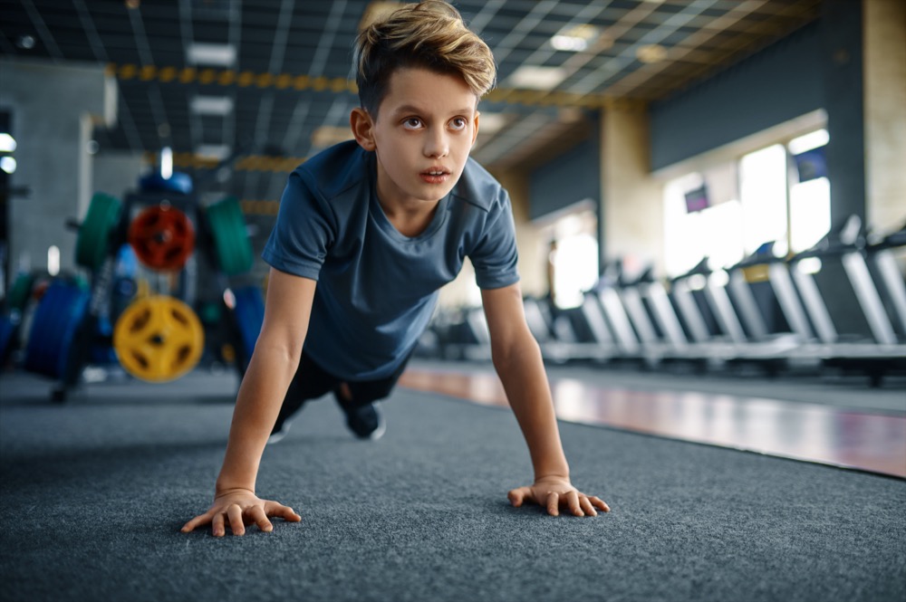 A boy in a gym doing push-ups